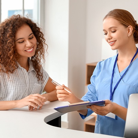 Dental office team member talking to mother at reception desk