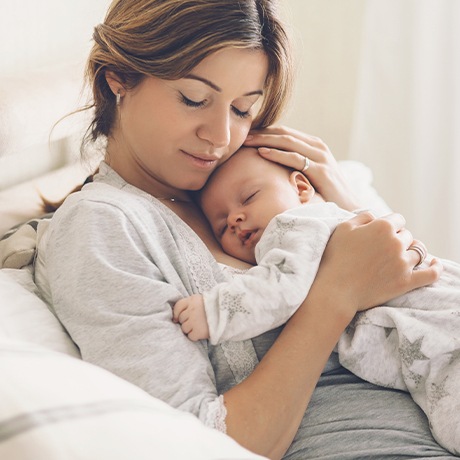 Mother holding sleeping baby after frenectomy treatment