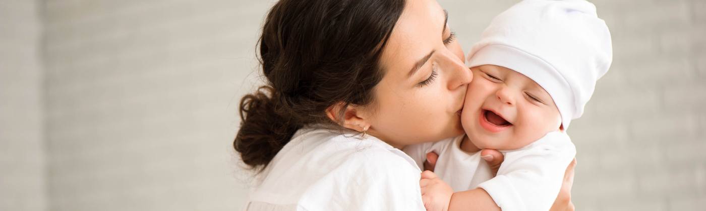 Mother kissing baby's cheek after lip and tongue tie treatment