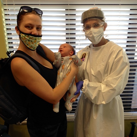 Doctor Davis smiling with mother and baby