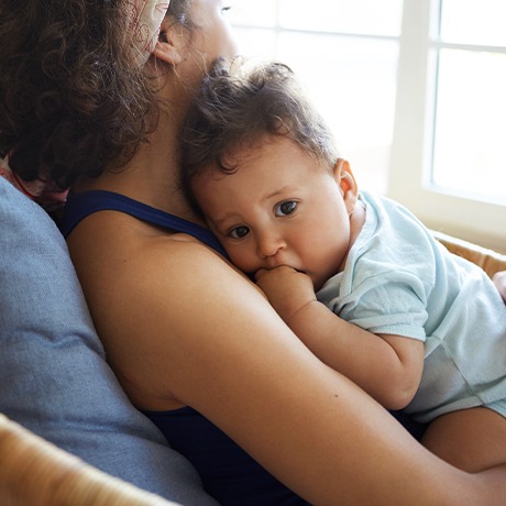 Mother holding baby who is chewing on fingers