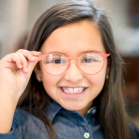Smiling child putting on glasses