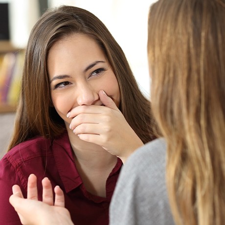 Woman covering her mouth while speaking