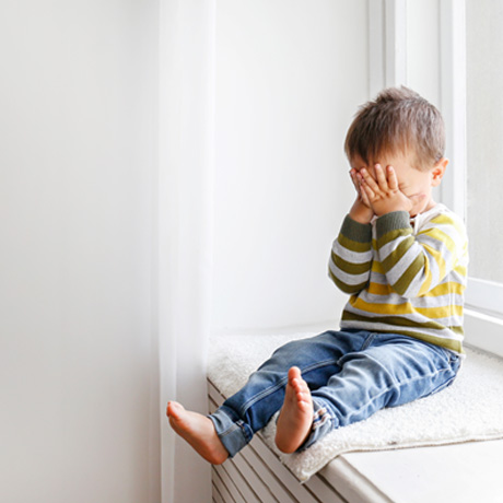 Upset toddler sitting next to window