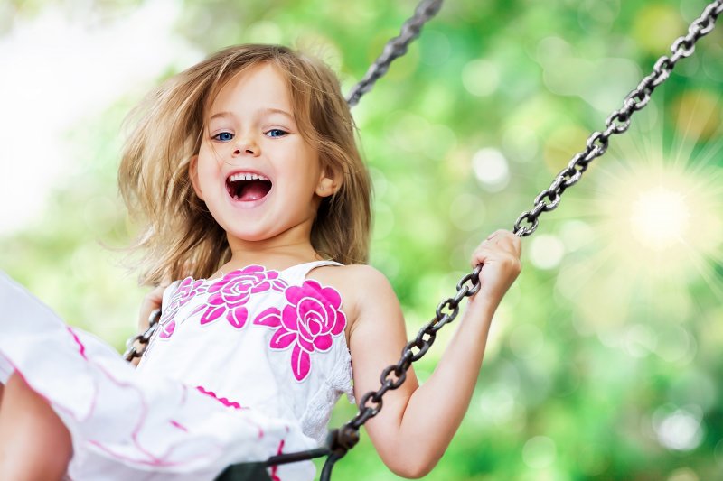 a young girl playing on a swing and smiling