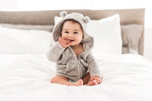 Smiling baby sitting on bed